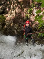 Canyoning through a waterfall with helmet and rope