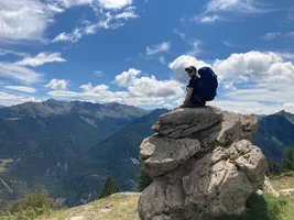 Sitting on a rock with a backpack, looking out over a mountain valley